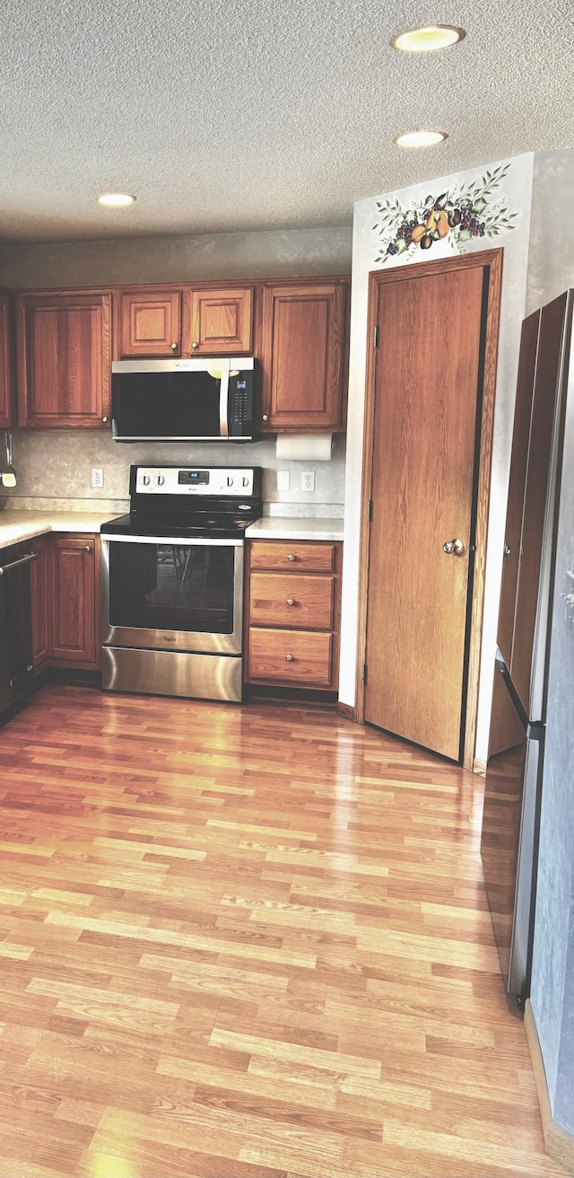13852 Jasmine Way, Rogers, MN 55374 - kitchen featuring stainless steel appliances, light wood-style flooring, light countertops, a textured ceiling, and brown cabinetry