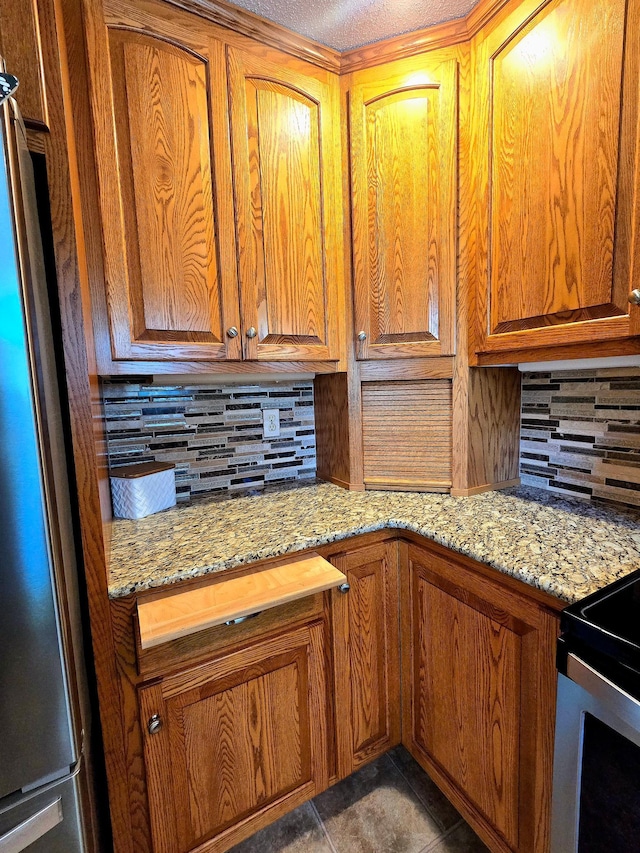 kitchen with freestanding refrigerator, decorative backsplash, and brown cabinetry