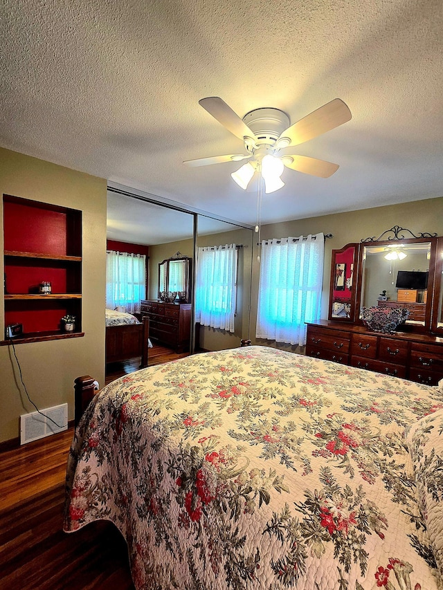 bedroom featuring wood finished floors, multiple windows, a textured ceiling, and ceiling fan