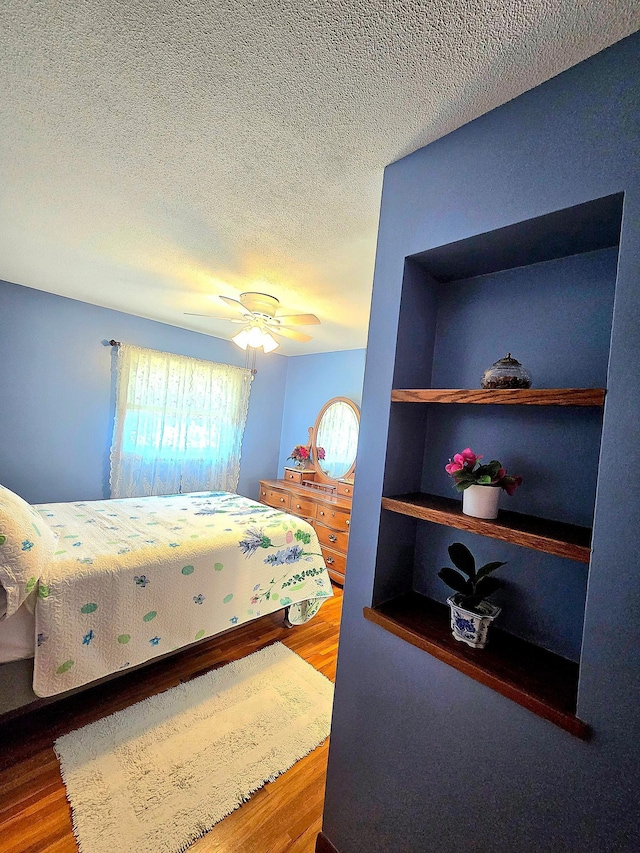 bedroom with wood finished floors, a textured ceiling, and ceiling fan