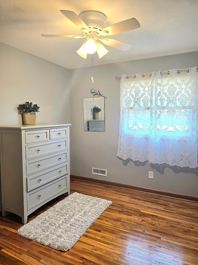 bedroom featuring dark wood-style floors, a ceiling fan, and baseboards