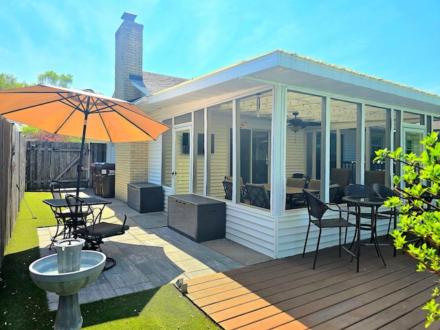 wooden terrace with a patio area, fence, a gate, and a sunroom