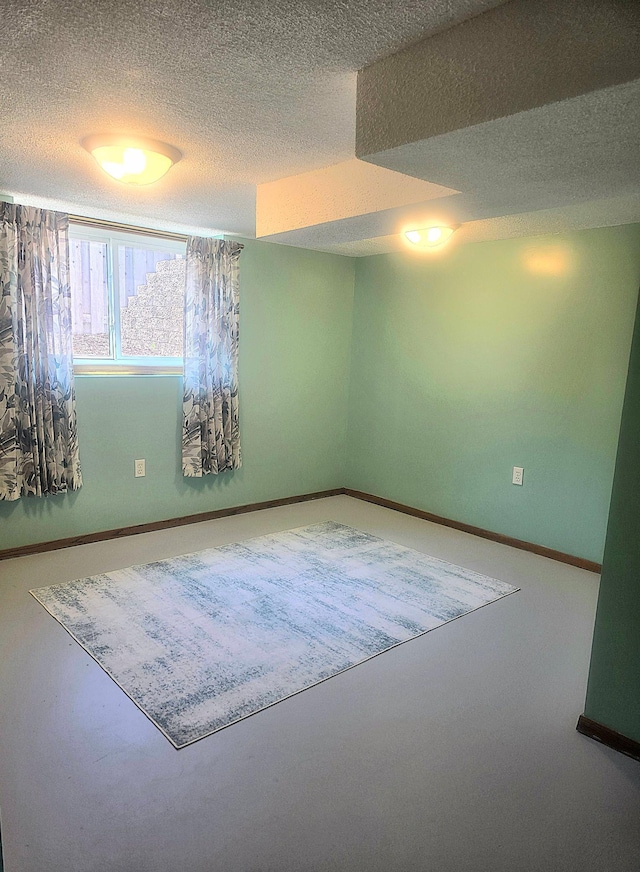 empty room featuring a textured ceiling and baseboards