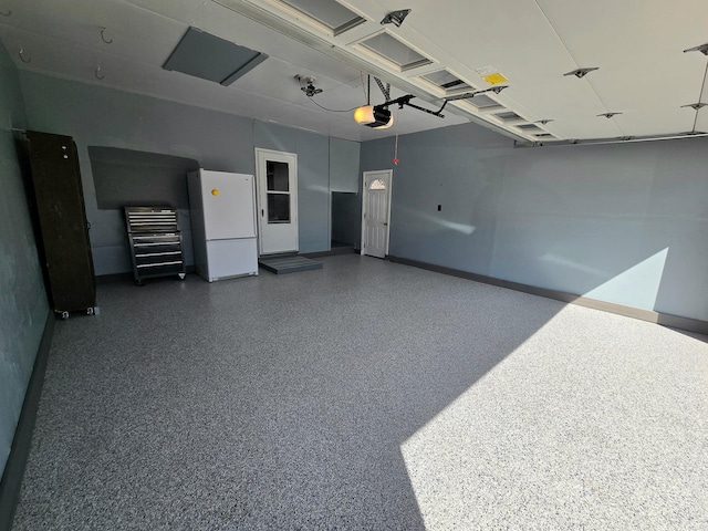 garage featuring freestanding refrigerator, a garage door opener, and baseboards