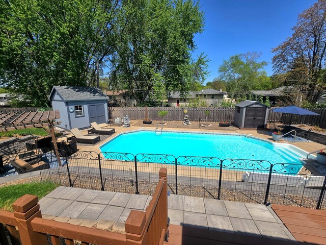 view of pool with a storage shed, an outbuilding, a fenced backyard, and a patio