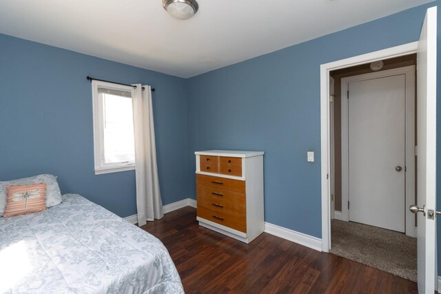 bedroom with dark wood-type flooring and baseboards