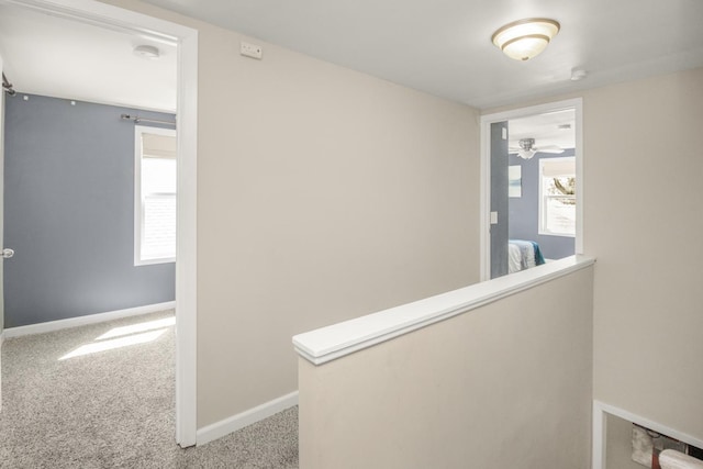 hall with carpet floors, an upstairs landing, and baseboards