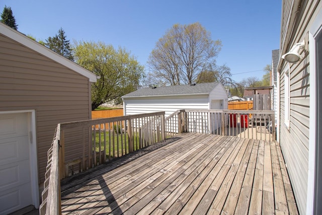 wooden deck with an outdoor structure, fence, and a garage