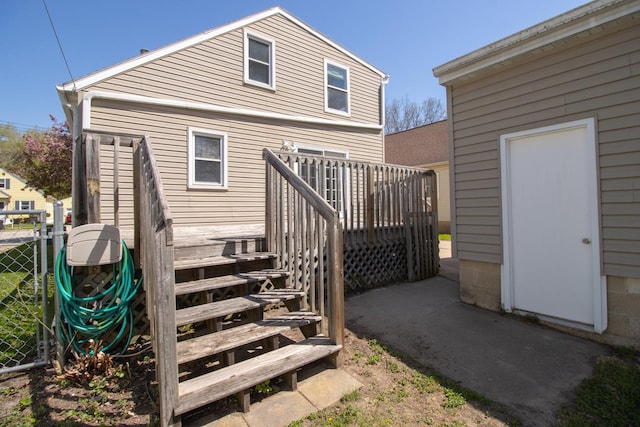 rear view of house with a deck, fence, and stairs