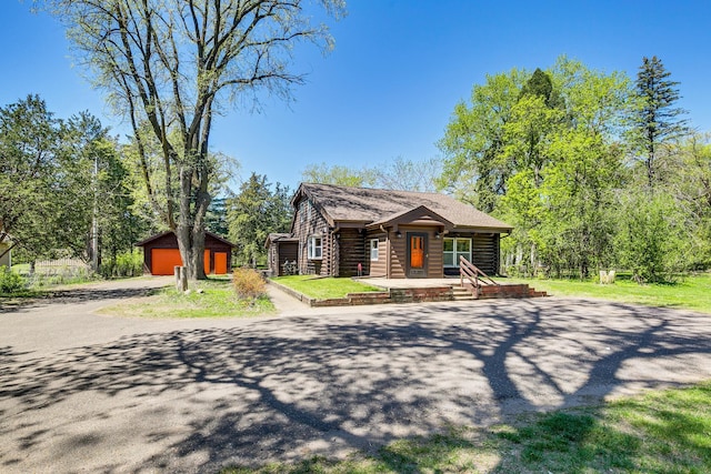 view of front of property featuring covered porch, a garage, an outbuilding, and driveway