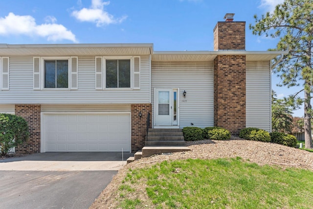1635 140th St, Burnsville, MN 55337 - bi-level home featuring brick siding, a chimney, concrete driveway, and a garage