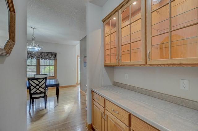 347 Glover Rd, Troy Twp, WI 54022 - kitchen with pendant lighting, a textured ceiling, baseboards, light wood finished floors, and light countertops