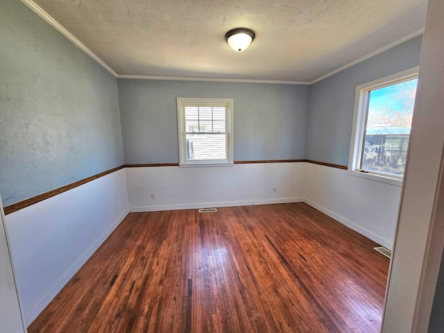 unfurnished room featuring hardwood / wood-style floors, ornamental molding, baseboards, and a textured ceiling