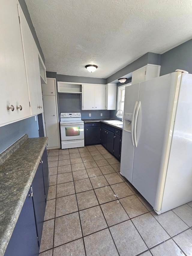 kitchen with white appliances, a sink, a textured ceiling, light tile patterned floors, and white cabinets
