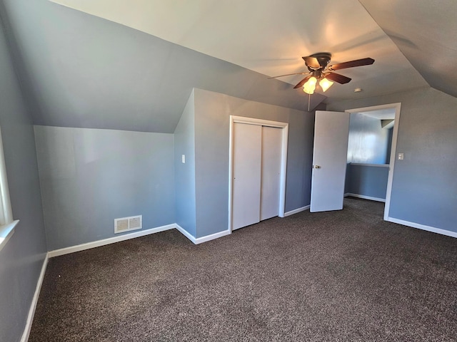 unfurnished bedroom featuring vaulted ceiling, baseboards, a closet, and dark carpet