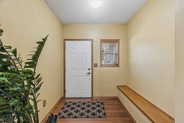 doorway featuring dark wood-type flooring, a textured ceiling, and baseboards