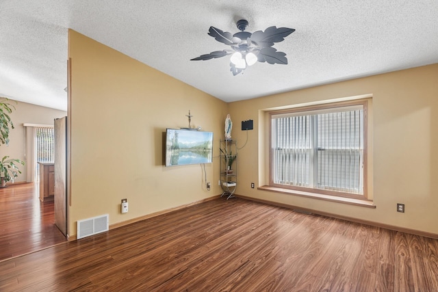 unfurnished room with lofted ceiling, a textured ceiling, wood finished floors, plenty of natural light, and ceiling fan
