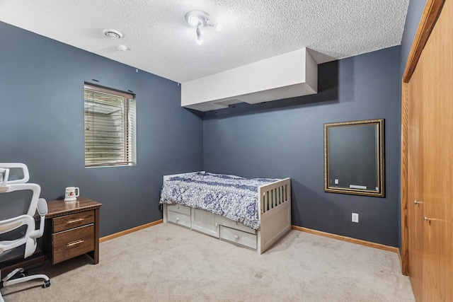 carpeted bedroom featuring a textured ceiling and baseboards