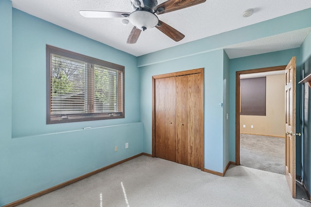 unfurnished bedroom featuring carpet flooring, a closet, baseboards, a ceiling fan, and a textured ceiling