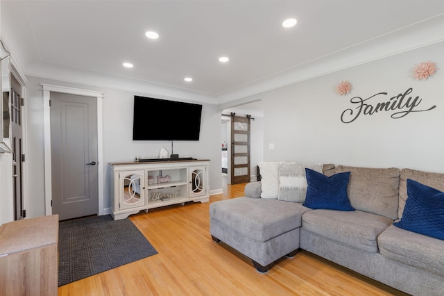 living room featuring light wood finished floors, a barn door, and recessed lighting