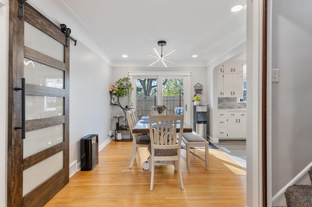 dining area featuring crown molding, light wood-type flooring, a barn door, and recessed lighting