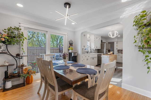 dining room with light wood finished floors, recessed lighting, baseboards, and a notable chandelier