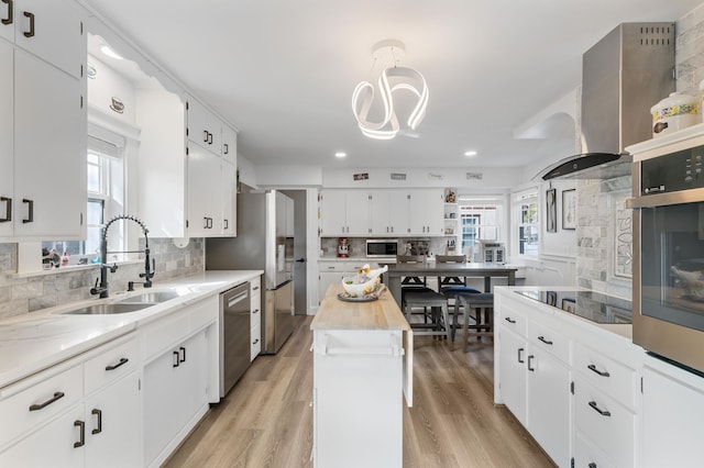 kitchen with recessed lighting, a sink, backsplash, white cabinets, and appliances with stainless steel finishes