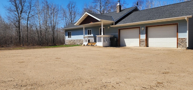 view of front of house featuring a chimney, stone siding, roof with shingles, and a garage