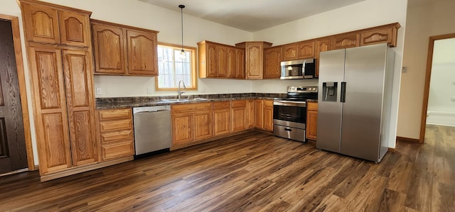 kitchen featuring dark countertops, appliances with stainless steel finishes, a sink, and dark wood-type flooring