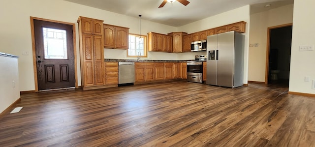 kitchen featuring a ceiling fan, dark wood-style flooring, dark countertops, and stainless steel appliances