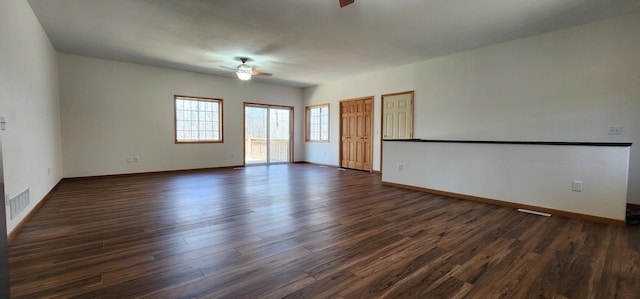 empty room featuring dark wood-style flooring, baseboards, a ceiling fan, and visible vents