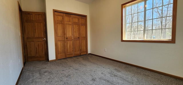 unfurnished bedroom with carpet floors, a closet, baseboards, and multiple windows
