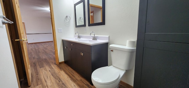 bathroom featuring toilet, baseboards, vanity, and wood finished floors