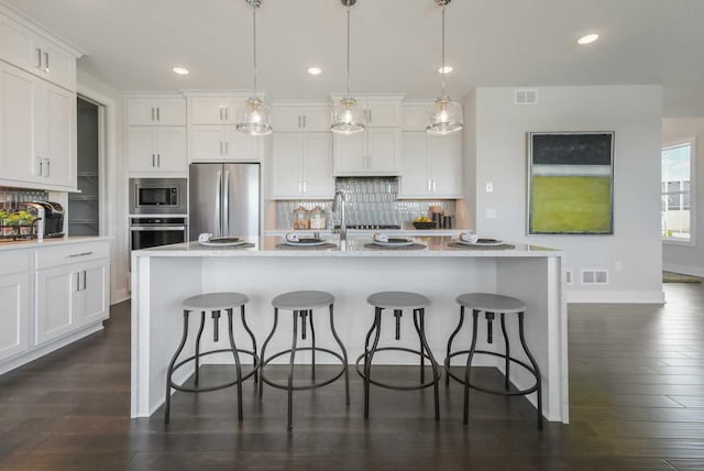 10833 38th Trl N, Lake Elmo, MN 55042 - kitchen with appliances with stainless steel finishes, backsplash, a breakfast bar, white cabinets, and recessed lighting