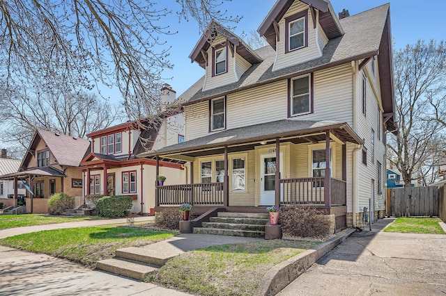 view of front of house with a porch, roof with shingles, and fence
