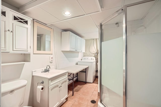 bathroom featuring washer / dryer, tile patterned floors, toilet, and a shower stall