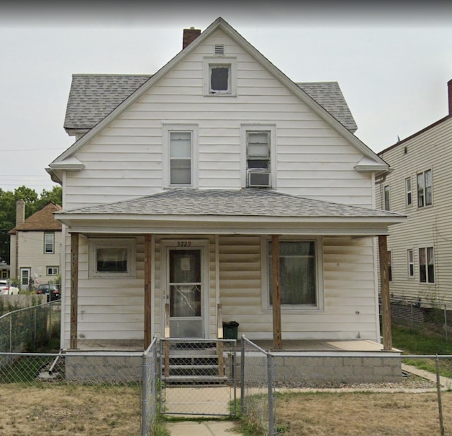 view of front facade with a porch, a gate, a fenced front yard, a chimney, and a shingled roof