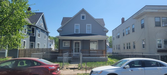 3229 Chicago Ave, Minneapolis, MN 55407 - view of front facade featuring covered porch, a fenced front yard, and a shingled roof