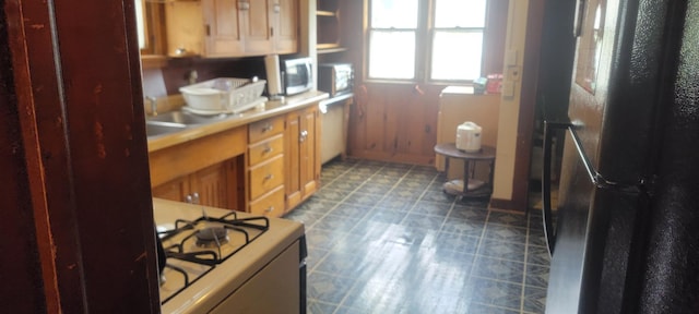 3229 Chicago Ave, Minneapolis, MN 55407 - kitchen with freestanding refrigerator, range with gas stovetop, white microwave, light countertops, and light floors