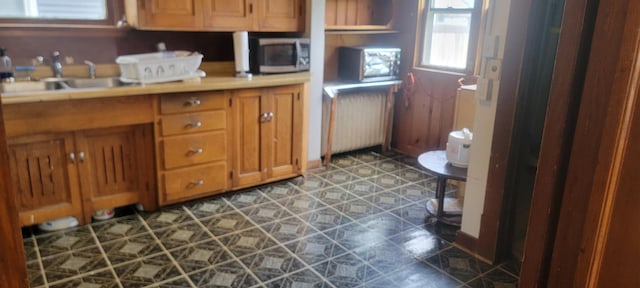 3229 Chicago Ave, Minneapolis, MN 55407 - kitchen featuring stainless steel microwave, a sink, radiator, brown cabinetry, and light countertops