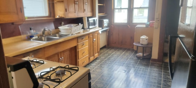 3229 Chicago Ave, Minneapolis, MN 55407 - kitchen featuring white appliances, brown cabinetry, a sink, and plenty of natural light