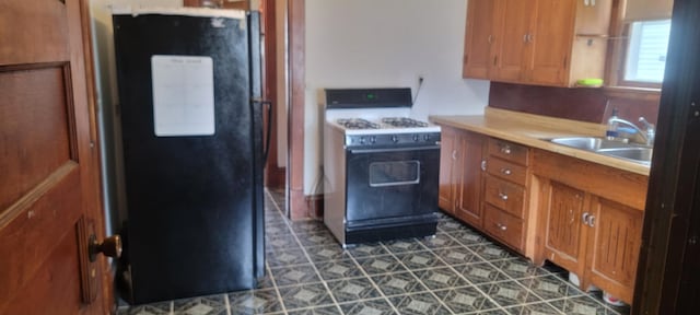 3229 Chicago Ave, Minneapolis, MN 55407 - kitchen featuring freestanding refrigerator, range with gas cooktop, a sink, brown cabinets, and light countertops