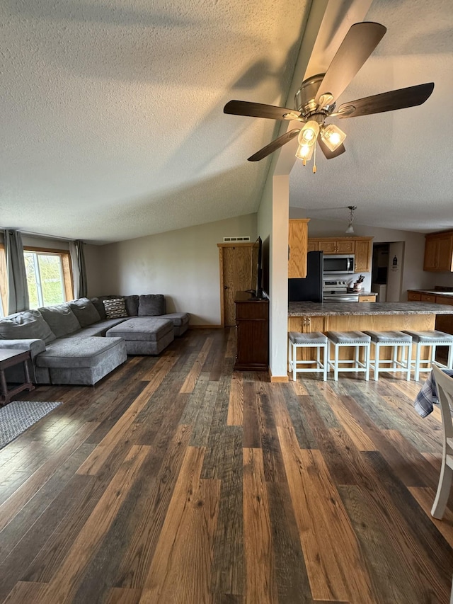 living room featuring lofted ceiling, dark wood-style floors, a textured ceiling, and a ceiling fan