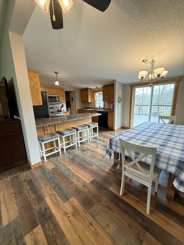 dining room with a textured ceiling, plenty of natural light, wood finished floors, a chandelier, and baseboards