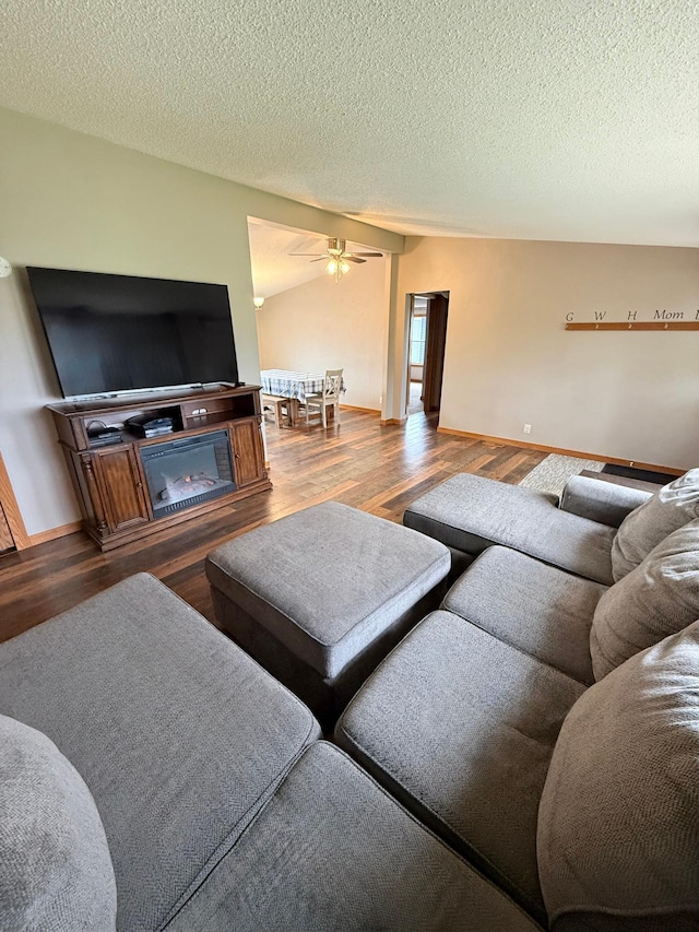 living room with wood finished floors, a ceiling fan, baseboards, and a textured ceiling
