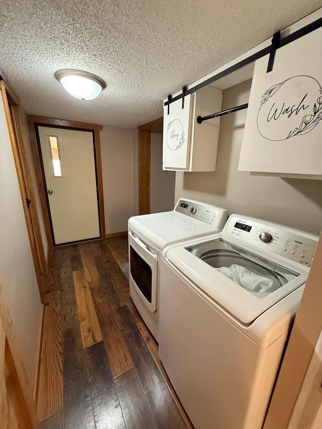 clothes washing area featuring washing machine and clothes dryer, a textured ceiling, dark wood-style flooring, and baseboards
