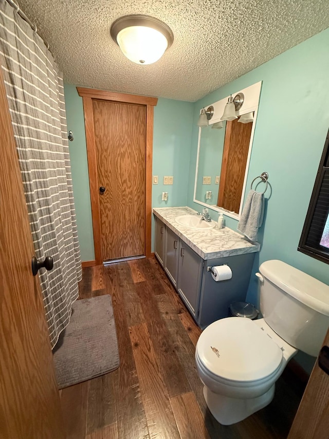 full bathroom with wood finished floors, toilet, a textured ceiling, and vanity