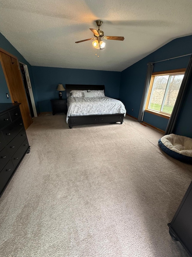 bedroom featuring lofted ceiling, light colored carpet, a textured ceiling, and ceiling fan