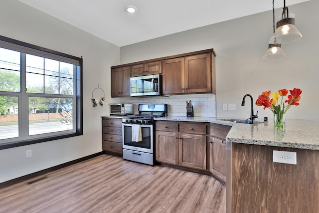 10240 3rd St NE Unit D, Blaine, MN 55434 - kitchen featuring stainless steel appliances, a sink, a peninsula, light wood-type flooring, and decorative backsplash