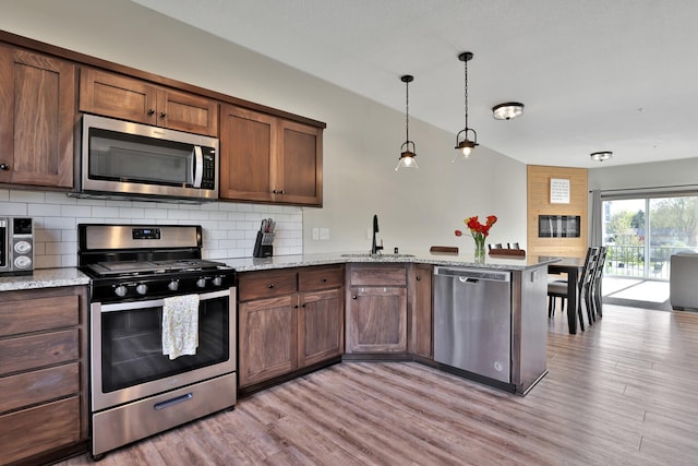 10240 3rd St NE Unit D, Blaine, MN 55434 - kitchen with appliances with stainless steel finishes, a sink, a peninsula, decorative backsplash, and light wood finished floors